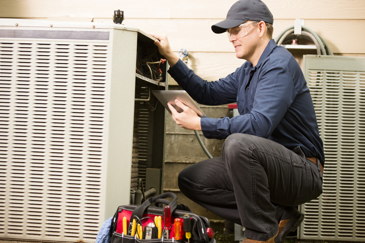Air conditioner repairman works on home unit. Blue collar worker. | Pro Comfort Heating & Cooling